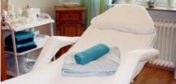 Behandlungsliege mit blauen Handtüchern in einem ruhigen Spa- oder Massageraum.