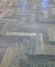 Parkettboden in Fischgrätenmuster aus Holz mit verschiedenen Brauntönen.