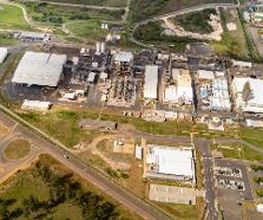 Vista aérea de um complexo industrial rodeado por estradas e áreas verdes.