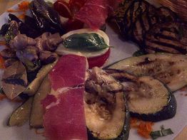 Teller mit gegrilltem Gemüse, Aufschnitt, Tomaten und einer Basilikum-Mozzarella-Scheibe.