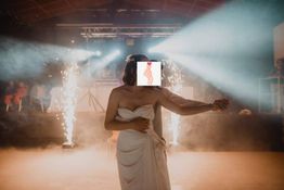 Une mariée en robe danse au milieu de feux d'artifice intérieurs sur une scène enfumée.