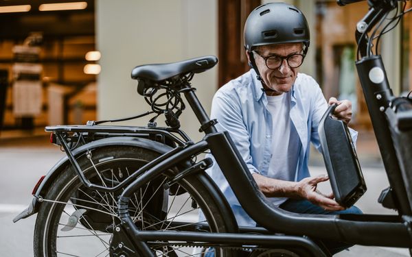 Alter Mann klemmt seine Batterie in sein e-bike