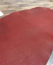 Hoja de cuero rojo extendida sobre un suelo de madera.