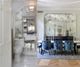 Luxurious bathroom and dining room with mirrored walls and elegant blue chairs.