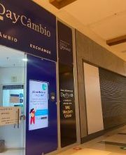 Fachada de casa de câmbio em shopping, com letreiros iluminados e portas de metal fechadas.