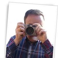 Persona con camisa a cuadros tomando una foto con cámara réflex.