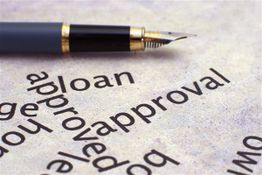 Fountain pen on paper with large printed words "loan" and "approval."