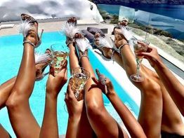 Frauen entspannen am Pool mit Sektgläsern, während sie stilvolle, weiße Sandalen tragen.