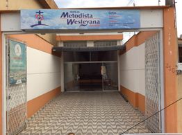 Entrada da Igreja Metodista Wesleyana com piso de ladrilho e fachada azul e branca.