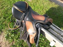 Pferdesattel und Helm auf Holzbank im Freien abgestellt.