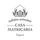 Logotipo de Casa Matricaria: dibujo de una casa con plantas, texto "xabóns artesáns" y "Galicia".