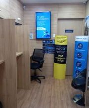 Sala com divisórias de madeira, cadeira preta, e cartazes informativos nas paredes.