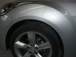 Silbergraues Auto, Vorderreifen und Radkasten in Nahaufnahme.