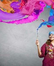 Frau malt mit einem Pinsel farbige Schwaden in der Luft auf grauem Hintergrund.