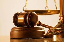 Martelo de juiz com balança dourada ao fundo, simbolizando justiça e equidade.