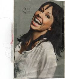 Lächelnde Frau mit weißer Bluse, Zeichnung eines Herzes auf dem Bild, vor grauem Hintergrund.