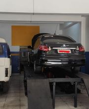 Carro preto em manutenção numa oficina, sobre uma plataforma elevatória.