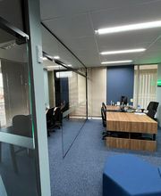 Sala de reunião moderna com mesa de madeira e cadeiras pretas, chão com carpete azul.