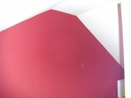 Rote Wand mit weißem Ecke in einem Raum mit schräger Decke.