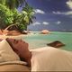Vrouw ontspant bij tropisch strand met palmbomen en turquoise zee, liggend op een handdoek.