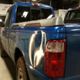 Blue pickup truck with a dented rear side panel in a garage setting.