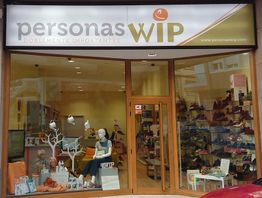 Tienda "Personas WIP" con escaparate de ropa y calzado. Hay un maniquí sentado.
