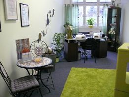 Nagelstudio mit Arbeitsplätzen, Pflanzen und Dekor. Gemütliche Sitzecke mit Tisch und Stühlen.