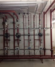 Rote Rohre und Ventile an einer Wand, Teil eines Heizungs- oder Wasserleitungssystems.