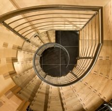 Wendeltreppe aus Holz mit Metallgeländer von oben betrachtet.