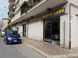 Auto blu parcheggiata davanti a un concessionario chiamato "ABIEFFE-CARS" in una strada cittadina.