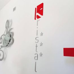 Logo su parete bianca con scritta "Kristal" e due stelle, decorazione floreale grigia.
