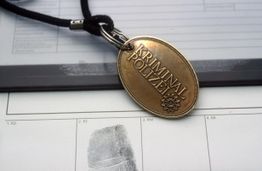 Anhänger mit "Kriminalpolizei" auf Fingerabdruck-Dokumentation liegend.