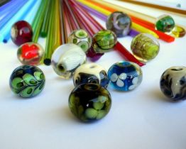 Bunte Glasperlen und Stäbe auf weißem Hintergrund, Kunsthandwerk, leuchtende Farben.