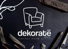 Sillón blanco decorativo con texto: "Dekorate. Vintage Room Design" sobre fondo oscuro con ramas.