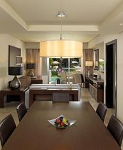 Comedor moderno con mesa, sillas, lámpara colgante y frutero. Cocina y sala al fondo.