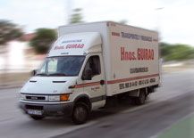 Camión de mudanzas blanco en movimiento con el texto "Transporte y Mudanzas Hnos. Guirao".