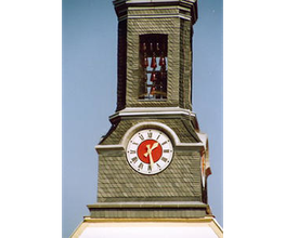 Kirchturm mit analoger Uhr und blauem Himmel im Hintergrund.