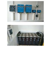 Sistema de baterías y controladores eléctricos en una pared blanca.