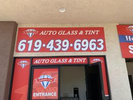 Auto shop entrance with "Auto Glass & Tint" and phone number in bold red signage.