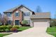 Two-story house with a brick facade, shingled roof, and two-car garage on a sunny day.