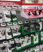 Scaffale di accessori per cellulari in un negozio, tra cui supporti per auto e cavi.