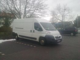 Weißer Lieferwagen parkt auf einem gepflasterten Parkplatz an einem bewölkten Tag.