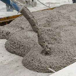 Pouring wet concrete onto a construction site.