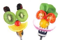 Deux visages souriants en fruits et légumes sur fourchettes.