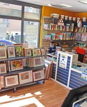 Interno di un negozio di stampe con scaffali di quadri e forniture per stampanti.