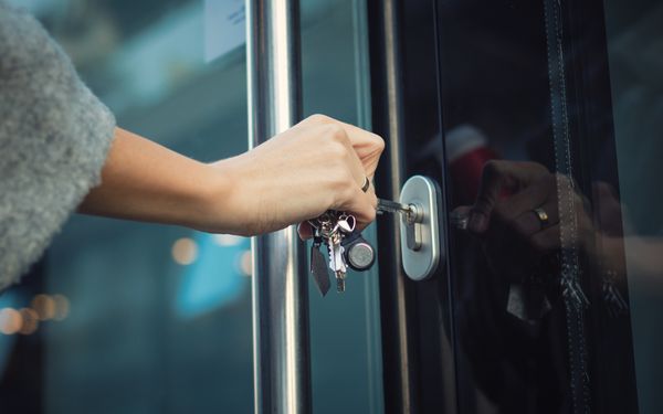 Frau sperrt Haustür mit einem Schlüssel auf.