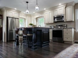 Elegant kitchen with dark island, pendant lights, and stainless steel appliances.