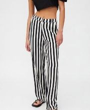 Mujer con pantalones de rayas blancas y negras, top negro y sandalias.