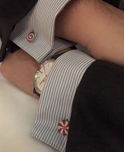 Mann mit gestreiftem Hemd, Uhr am Handgelenk und Manschettenknöpfen in Form von Zuckerstangen.