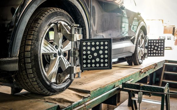 Achsenvermessung eines PKWs in einer Autowerkstatt auf einer Hebebühne.